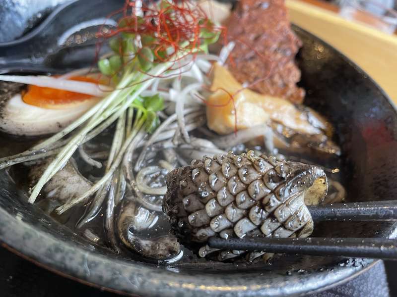 漆黒のイカスミ麺にトッピングされた松笠切りのイカ